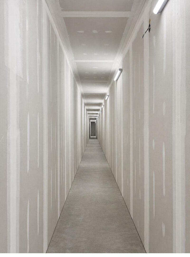 Long drywalled corridor with taped and finished walls