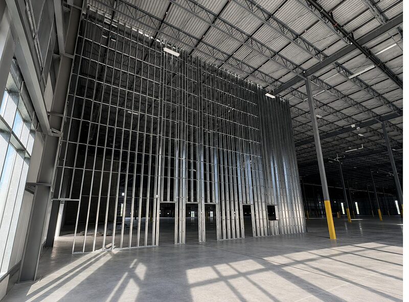 Tall interior steel-stud framing in an open commercial space